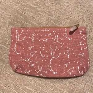 A pink make up bag with white astrology and a dark blue inside.